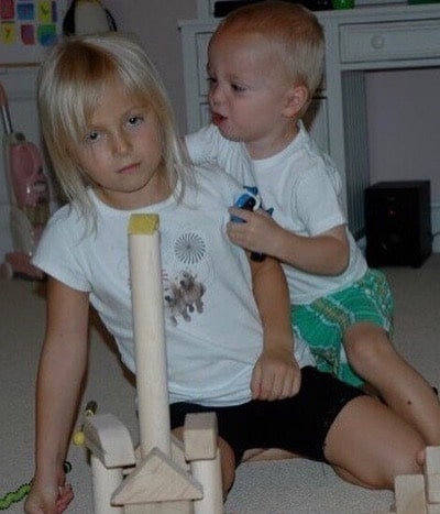 Will Buie Jr. in a white t-shirt and green shorts playing toy house with his sister Kaitlyn in white t-shirt and black shorts.